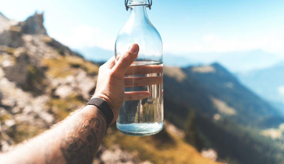 person holding empty clear glass bottle