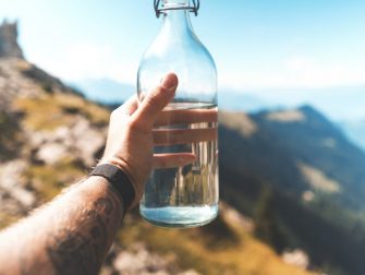 person holding empty clear glass bottle
